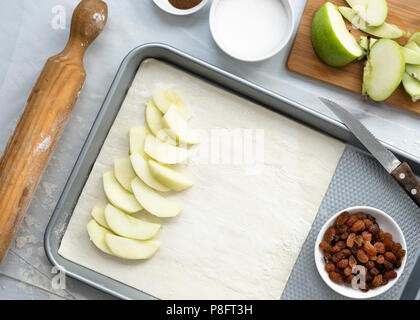 Preparation of apple strudel, apple slices layered on a sheet of pastry on a baking tray. Stock Photo