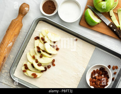 Preparation of apple strudel, apple slices and sultanas on a pastry sheet resting on a baking tray. Stock Photo