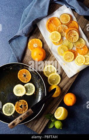 Oranges and lemons cut into slices and cooked in syrup to make candied fruit. Stock Photo