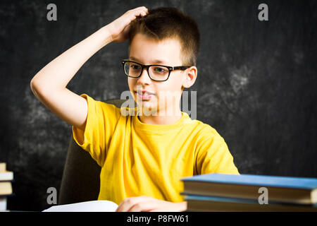 Cheerful boy with bunch of books thinking about school, education abstract Stock Photo