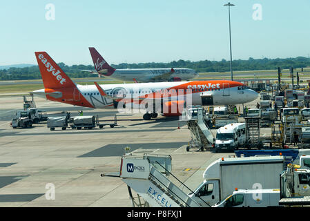 An EasyJet Airbus A320 G-UZHB on Stand and a Virgin Atlantic A330 G-VMNK Taxiing at Manchester International Airport Greater Manchester England UK Stock Photo