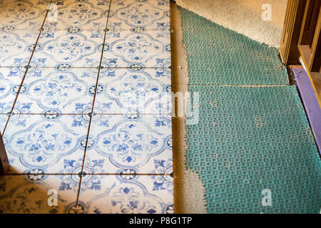 Decorative faded and rustic upscale blue and white patterned tiles being laid in the entry of a home during remodeling. USA. Stock Photo