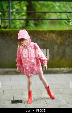 Adorable little girl in rain boots standing in a poodle Stock Photo