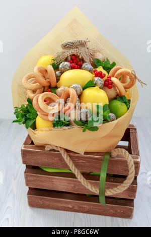 Bouquet consisting of honey, a bunch of bagels, mint leaves, lemons, lime, ginger and red currant in a wooden decorative box Stock Photo