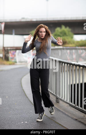 Female street dancer portrait in motion. Attractive young woman standing in dance pose in an urban scene. Full length. Selective focus. Stock Photo