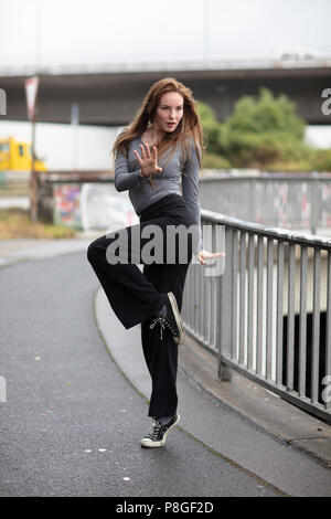 Female street dancer portrait in motion. Attractive young woman standing in dance pose in an urban scene. Full length. Selective focus. Stock Photo