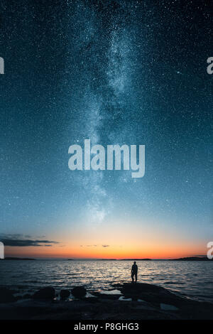 Silhouette of a man looking up on stars of the milky way with last light of sunset glows on the horizon Stock Photo
