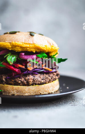 Black bean burgers with colourful toppings and hummus. Stock Photo