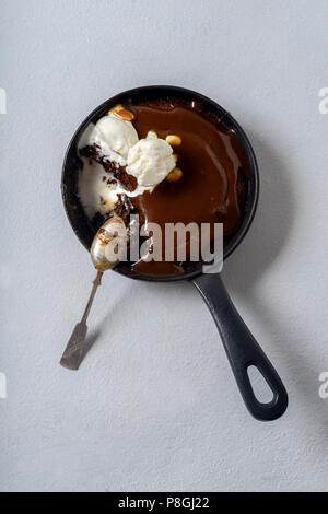 Brownie in a skillet with a scoop of vanilla ice cream, salted caramel and roasted peanuts Stock Photo