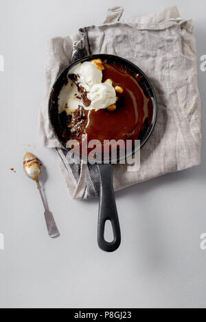 Brownie in a skillet with a scoop of vanilla ice cream, salted caramel and roasted peanuts Stock Photo