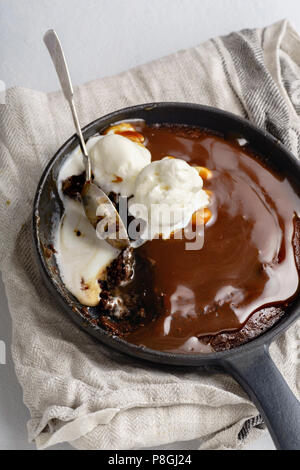 Brownie in a skillet with a scoop of vanilla ice cream, salted caramel and roasted peanuts Stock Photo
