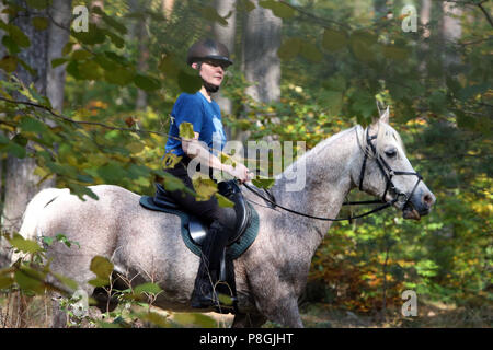 Zernikov, woman is riding on her horse in step through a forest Stock Photo