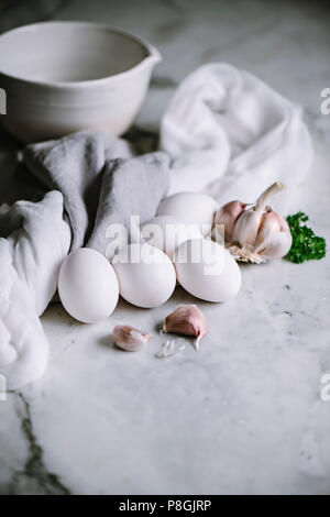 White eggs with garlic cloves on a marble worktop in a kitchen Stock Photo