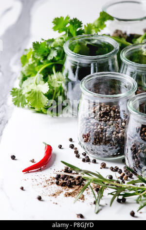 Variety of different black peppers allspice, pimento, long pepper, monks pepper, peppercorns and ground powder in glass jars with chili pepper and fre Stock Photo