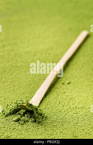 Green tea matcha powder in traditional bamboo spoon over powdering matcha as background. Stock Photo