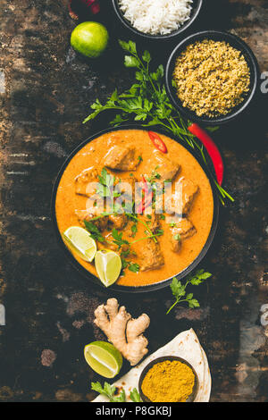 Traditional curry and ingredients on dark background. Curry, lime, ginger, chili, naan bread, rice, couscous, herbs and spices Flat lay Stock Photo