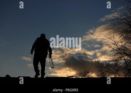 Berlin, Germany, Silhouette, craftsman stands with a saw on the roof of a gazebo Stock Photo