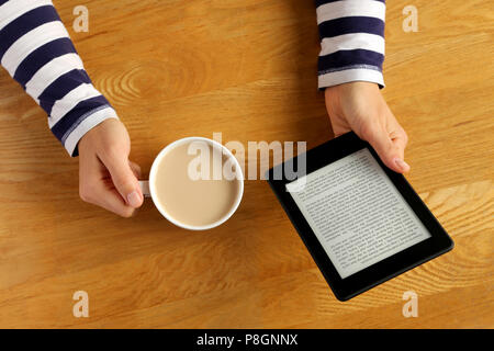 Woman reading a kindle electronic book and having coffee. Stock Photo