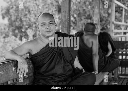 BURMESE MONKS uses the  teak U BEINS BRIDGE to commute across the Taungthaman Lake at sunrise - AMARAPURA, MYANMAR Stock Photo