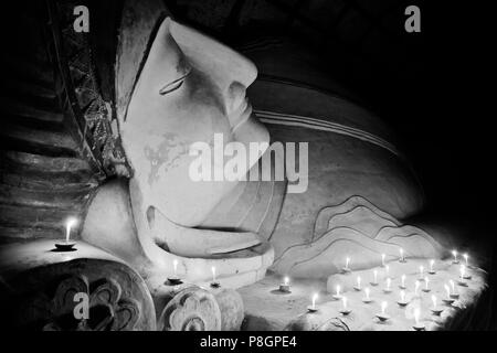 Candle offerings to 11th century reclining BUDDHA at SHINBINTHAHLYAUNG TEMPLE - BAGAN, MYANMAR Stock Photo