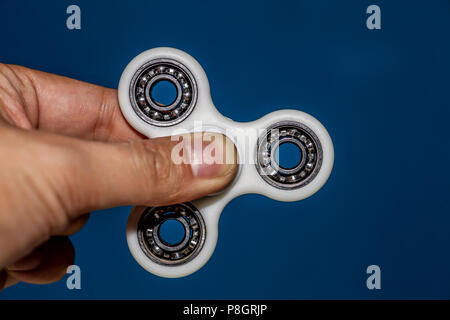 Hand holding a stationary fidget spinner with  blue background Stock Photo