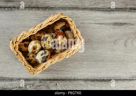 Table top view of quail eggs placed in small rectangular basket. Stock Photo
