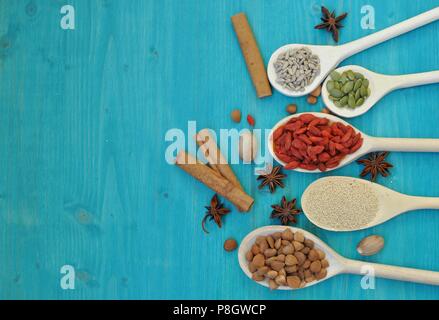 Concept of table with colorful aromatic seeds and fruits in wooden spoons, on blue background, flat lay, top table, copy space Stock Photo