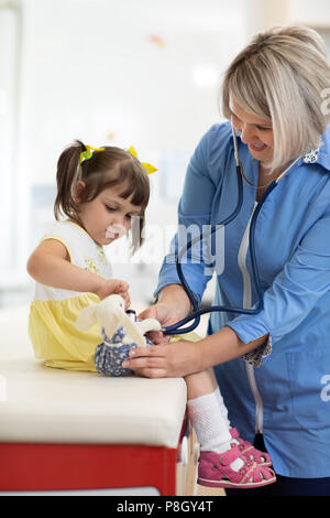 Doctor examining toy and little girl using stethoscope Stock Photo