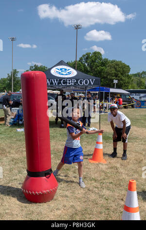 Detroit, Michigan USA - 11 July 2018 - Officers of the U.S. Customs and Border Protection encourage youth to beat a human-sized punching bag with a baton. The officers encouraged the action to continue even after the bag was laying on the ground. CBP had a booth at the annual Metro Detroit Youth Day, which draws thousands of school children for a day of food, games, science demonstrations, and other activities. Credit: Jim West/Alamy Live News Stock Photo