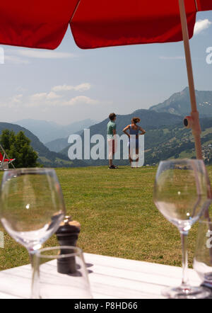 A Young Couple Enjoying the Mountain View in the Garden at Le Chasse-Montagne with Tables Set with Wine Glasses in Les Gets Haute-Savoie France Stock Photo
