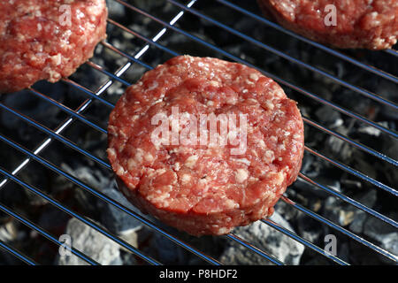 Close up raw beef or pork meat barbecue burgers for hamburger cooked grilled on bbq grill, high angle view Stock Photo