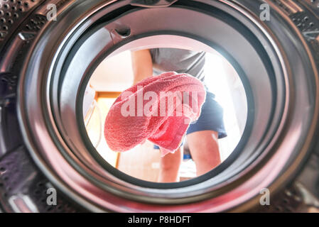 Young man doing laundry view from the inside of washing machine Stock Photo
