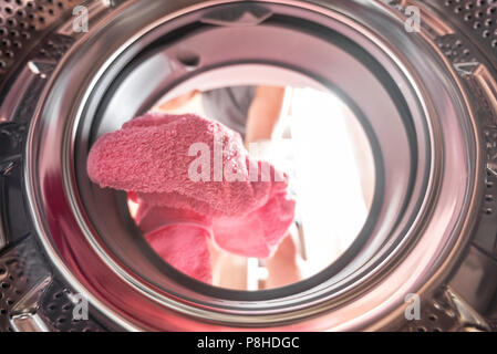 Young man doing laundry view from the inside of washing machine Stock Photo