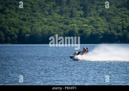 A fast jet propelled personal watercraft skimming over the water on Lake Pleasant, NY in the Adirondack Mountains. Stock Photo