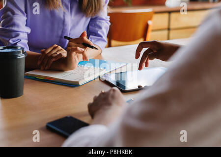 Two unrecognizable people working on a digital tablet. Close up of female hands using tablet pc. Stock Photo