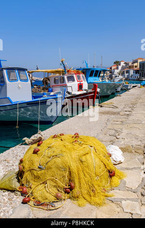 A yellow fishing net in front of the boats in Halki harbor. Stock Photo