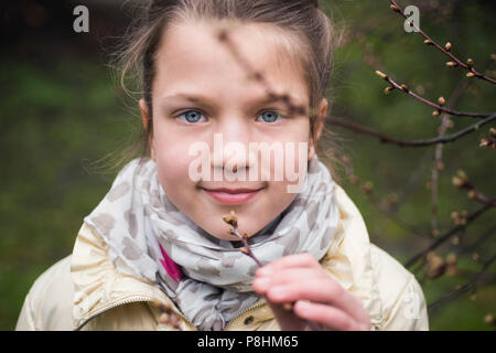 girl breathes in smell of fresh tree buds by early springtime Stock Photo