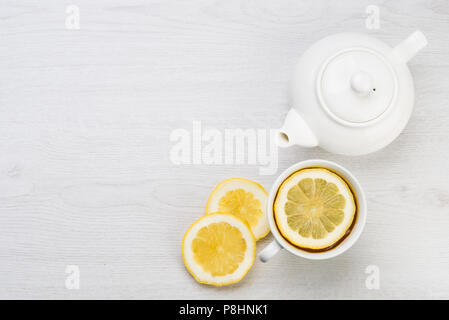 cup of tea with lemon slices and teapot on table Stock Photo