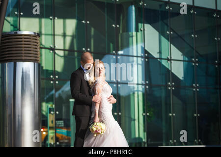 bride and groom holding each other near futuristic building Stock Photo