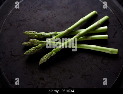 Fresh raw asparagus spears resting on metal plate Stock Photo