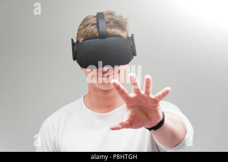 Man wearing virtual reality goggles on gray background. Student using VR headset. Stock Photo