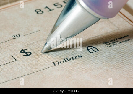 Close-up of a person filling out a dollar amount on a check, focus is sharp and on the pen tip and the dollar word and symbol. Stock Photo