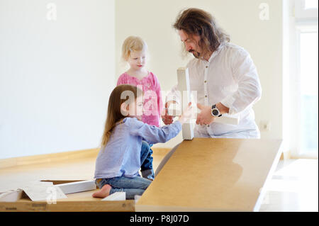 Happy father and his two daughters assembling a table together Stock Photo