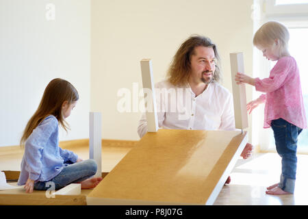 Happy father and his two daughters assembling a table together Stock Photo