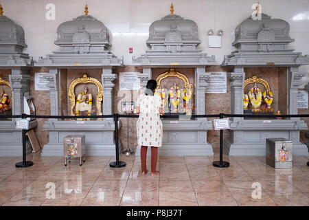 A woman praying and meditating in front of statues of gods and goddesses at the Hindu Temple Society in Flushing, Queens, New York City. Stock Photo