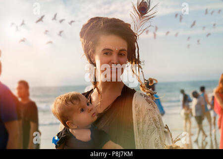 A smiling hippie young woman in crowed with dread-locks and a little baby, yearly Arambol Freak Show, 8th February 2018, India Stock Photo