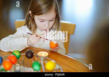 Adorable little girl coloring an Easter egg using wax and dyes Stock Photo