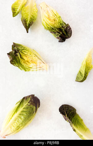 Top view of whole and halved Ruby Gem Lettuce on light gray background with copy space. Stock Photo