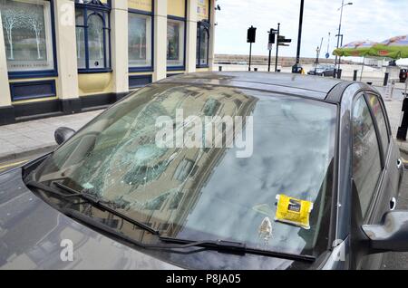 a car with a smashed windscreen and parking ticket in margate side street kent UK Stock Photo
