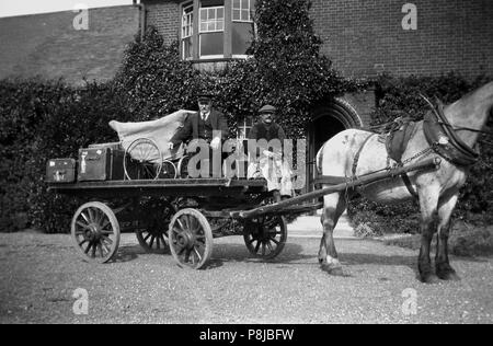 1930s, historical picture, on the driveway outside a large house two male servants sit on the back of a horse and cart loaded with luggage trunks of the era and a covered pram, England, UK. Stock Photo